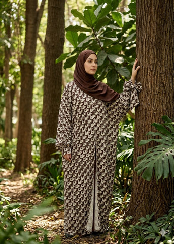 Modest woman wearing a printed brown CrepeLoom Farasha 3-piece abaya set with ribbon sleeves and matching hijab in a forest setting.
